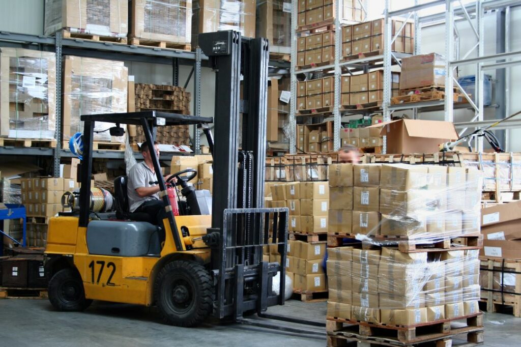 Warehouse worker lifting a pallet with a forklift